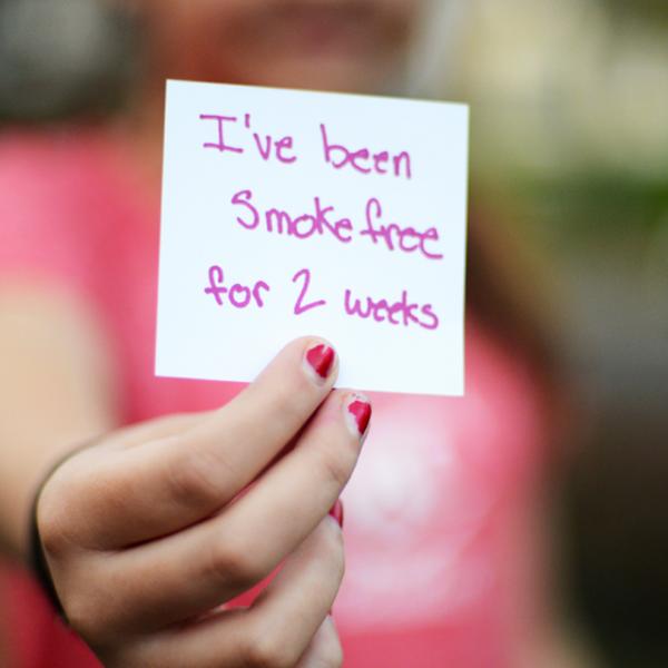 A person holds up an index card that reads "I've been smokefree for 2 weeks: