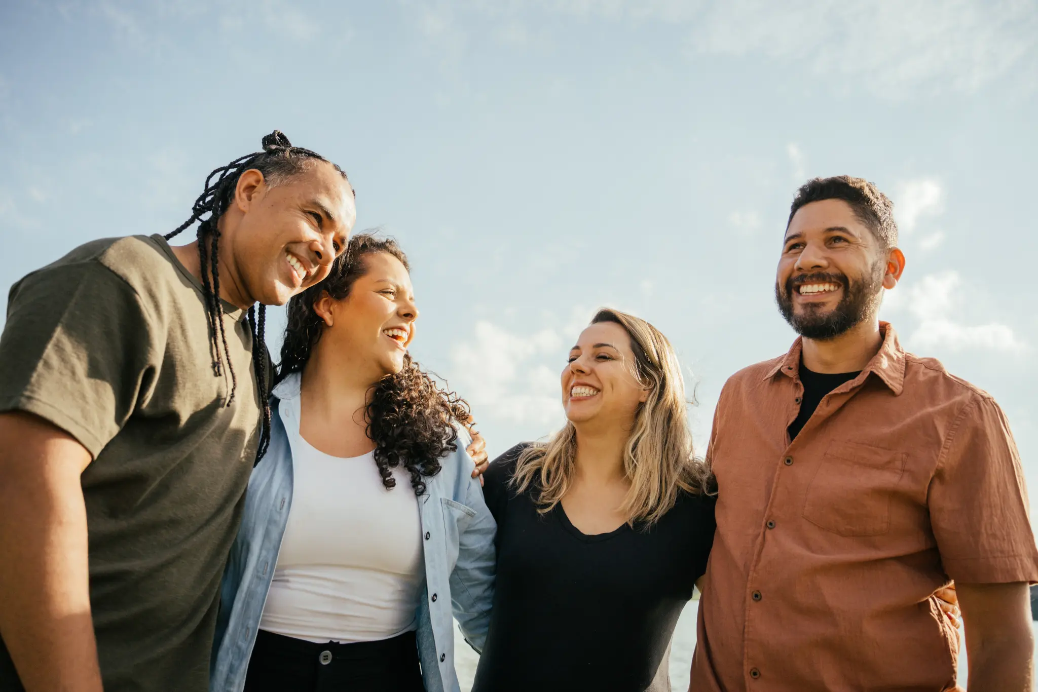 An image of four adults smiling and linking arms.