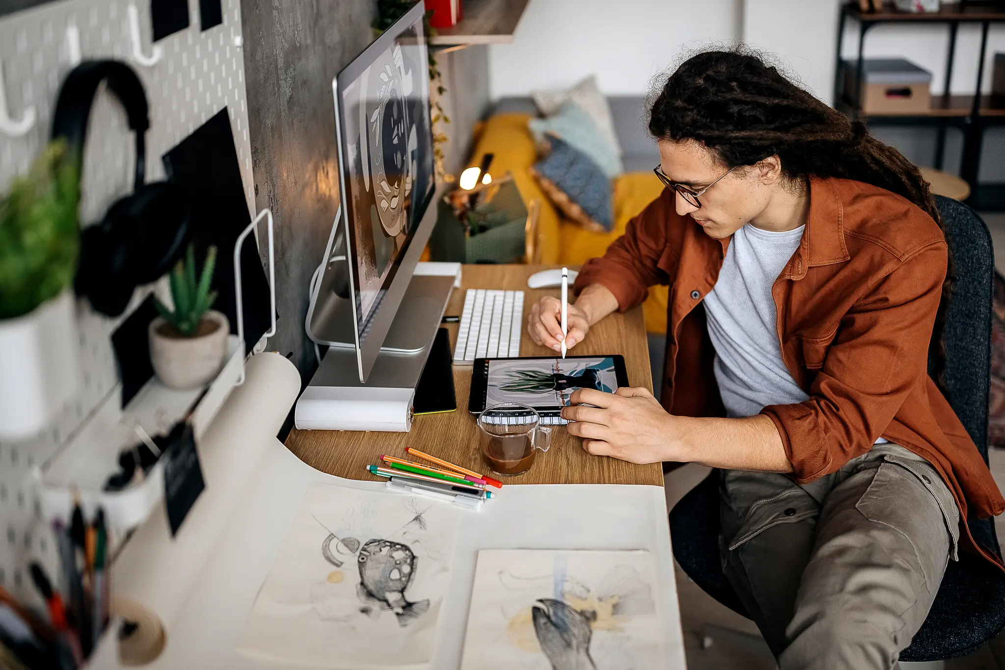 Image of a person seated at a desk making art on a graphics tablet.