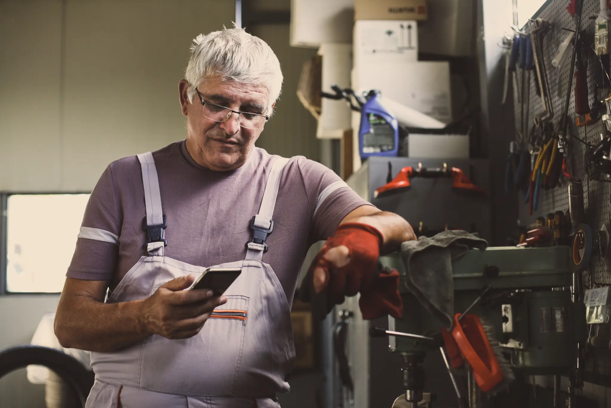 Image of a man consulting his phone while taking a break in his workshop.