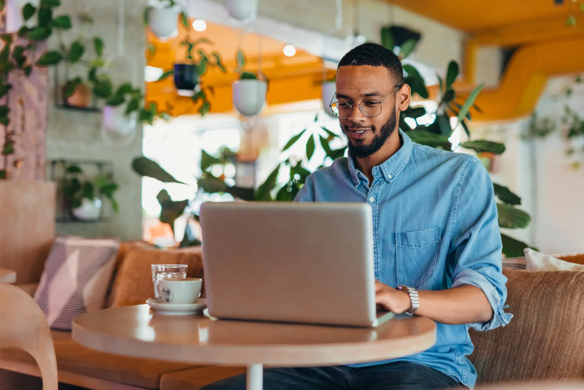 Image of a young man working on a laptop in a colorful coffee shop.