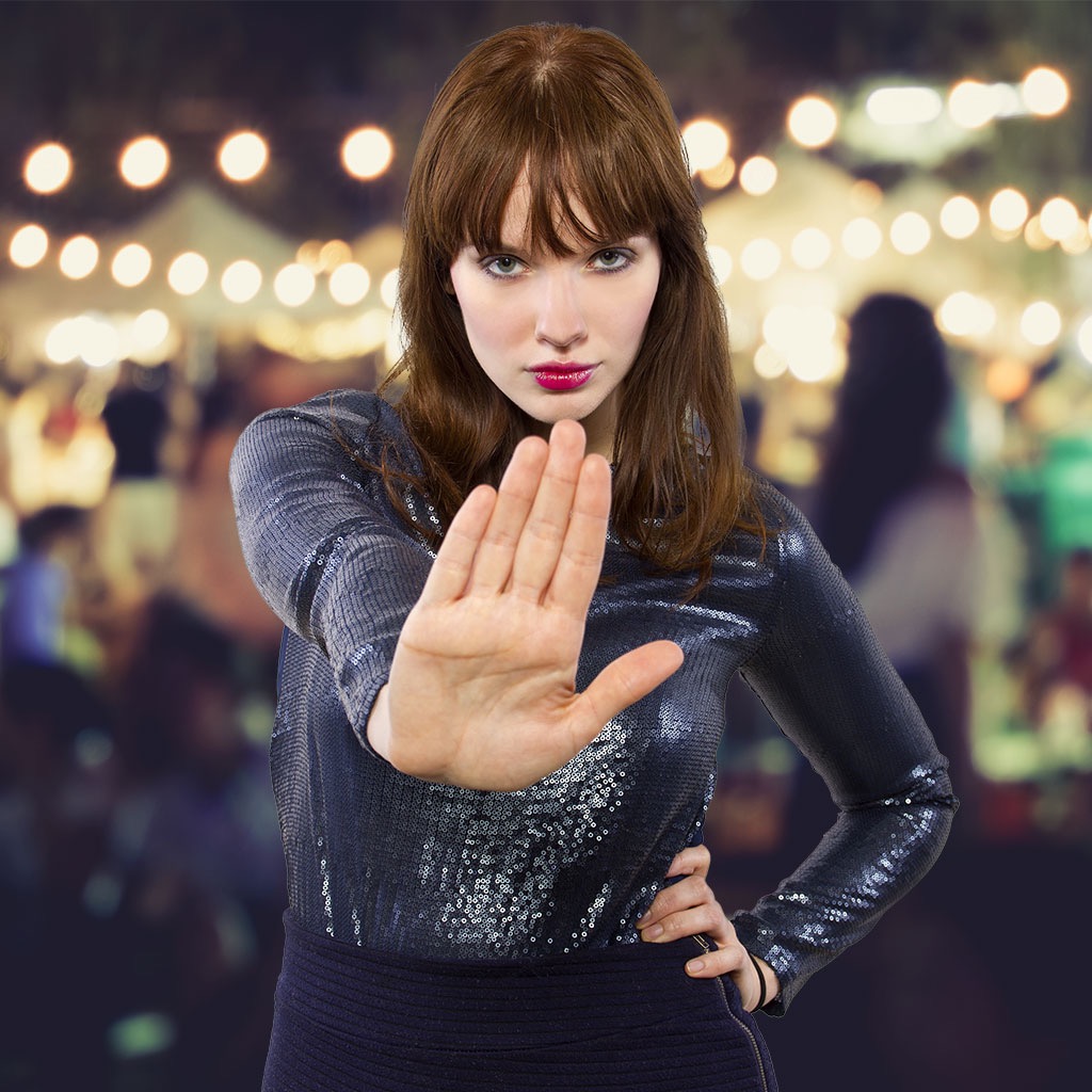 woman in front of outdoor bar holding up hand in a stop gesture