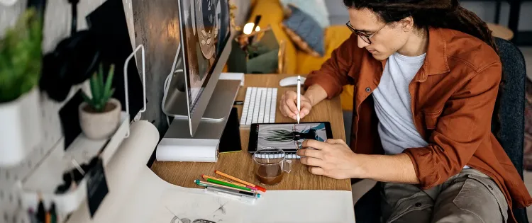 Image of a person seated at a desk making art on a graphics tablet.