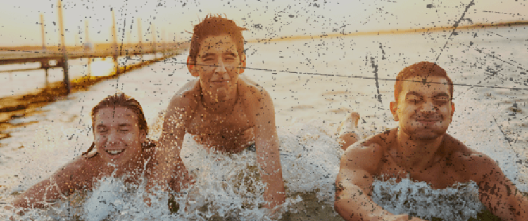 Three teenage boys body surfing in the ocean