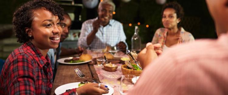 Photo of a family eating dinner together happily outside in the evening