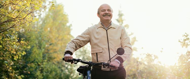 Un hombre mayor caminando con una bicicleta.
