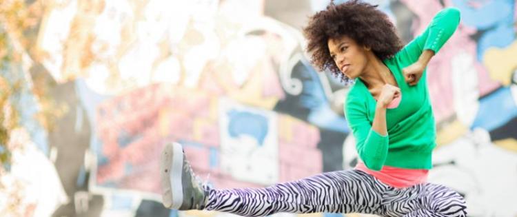 Photo of a woman wearing zebra-striped leggings jumping up and kicking in the style of kick boxing.