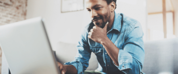 Photo of a man looking at his laptop while sitting on a couch