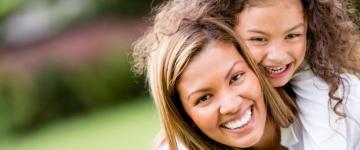 Photo of a mom giving her daughter a piggyback ride.