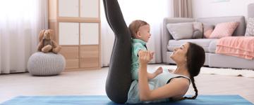 A woman on a yoga mat with her baby at home