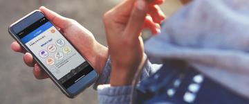 A photo of hands holding a smartphone with the Smokefree QuitSTART app on the screen.