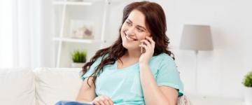 Photo of a woman sitting on the couch, talking on her cell phone.