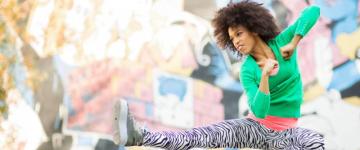 Photo of a woman wearing zebra-striped leggings jumping up and kicking in the style of kick boxing.