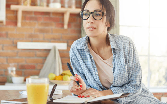 Photo of a dark haired woman using a day planner in her kitchen