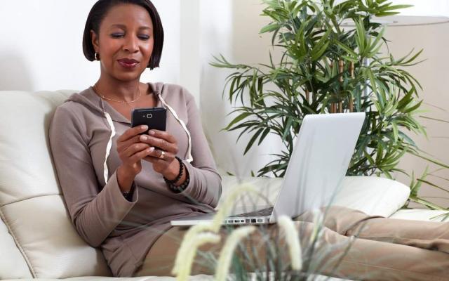 African American woman looking at phone at home