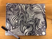 Photo of a pen resting on a sketchbook with abstract doodles