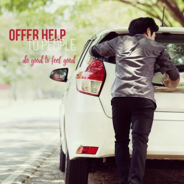 A man is pushing a car along the side of a well-lit street. Text to the left of the car reads "Offer help to people do good to feel good"