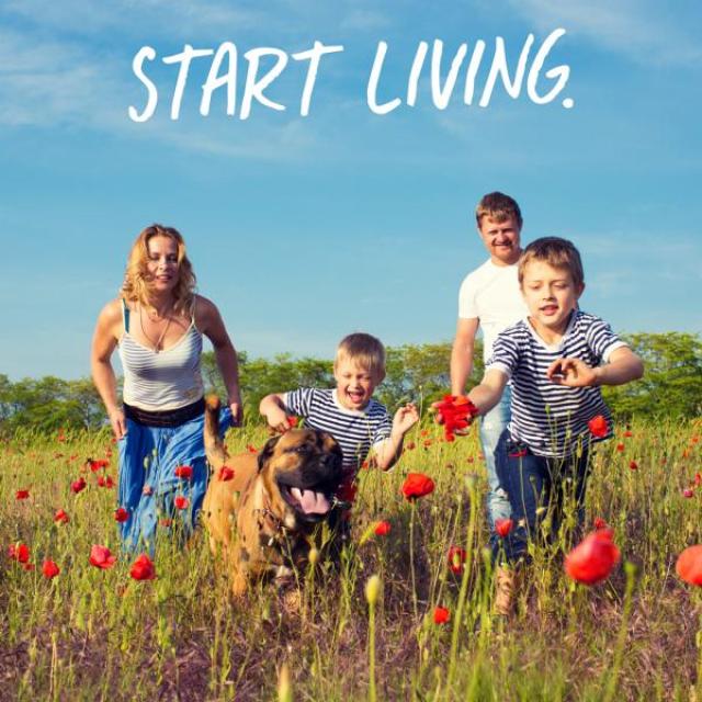 An image of a family and their dog running through a field with flowers.  Caption reads, "Start living."